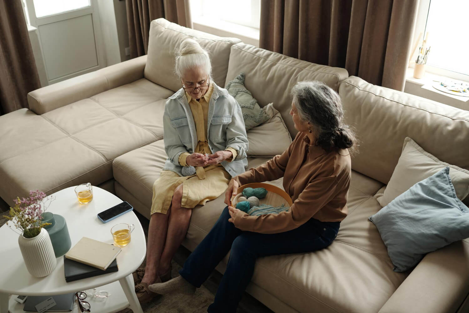 Two senior women sitting comfortably on a clean sofa in a well-maintained facility.