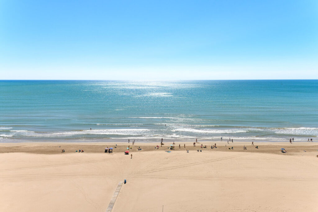 Clean, sandy Delaware beach with clear skies and shoreline view.